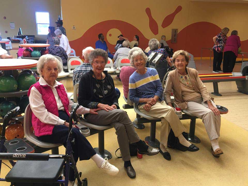 four senior women sitting at a bowling alley